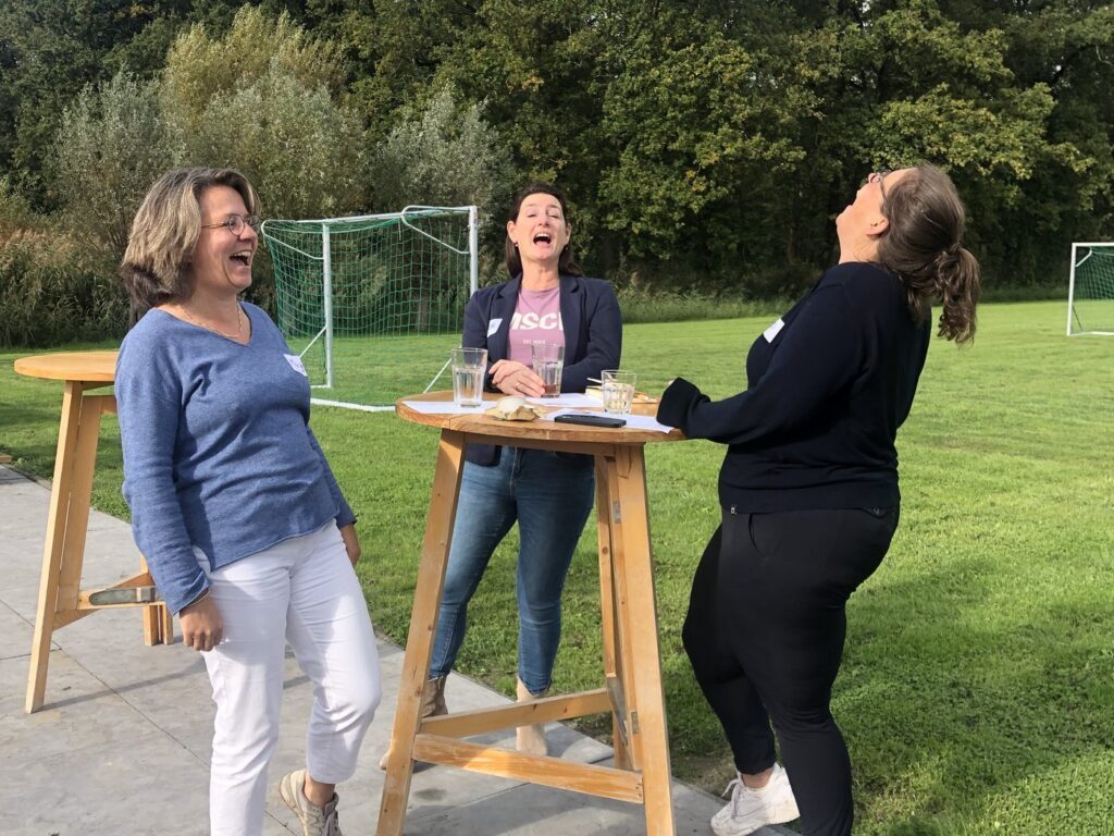 Deelnemers praten na bij een statafel buiten