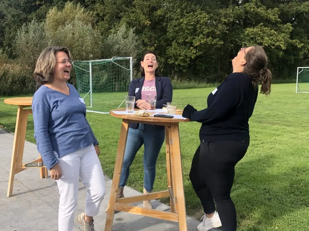 Deelnemers praten na bij een statafel buiten
